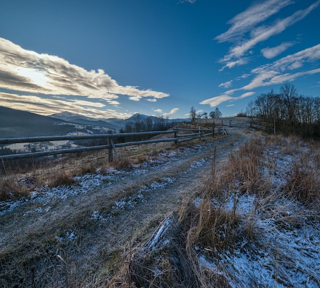 Winter komt eraan Laatste goede weerdagen herfst berglandschap ochtend vredig pittoresk tafereel Vuile weg van heuvels naar het dorp Hoverla en Petros Oekraïense Karpaten bergen in de verte