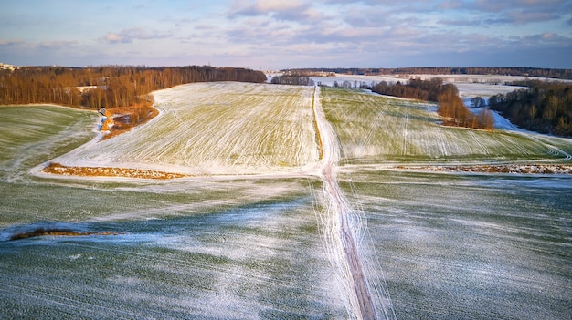 Winter landbouwgebied onder de sneeuw. Luchtscène. December Landelijk landschap. Platteland weg bovenaanzicht. Minsk regio, Wit-Rusland