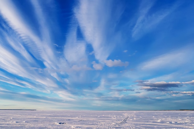 Winter landscape over frozen river with blue bright sky and white clouds