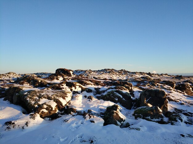 アイスランドの冬の風景。コケに覆われた固まった溶岩の畑は雪に覆われています。