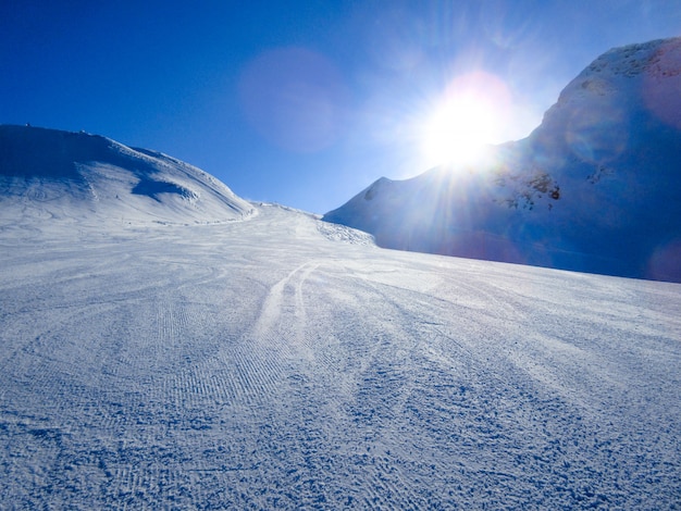 山の冬の風景です。山は晴れた冬の日に雪で覆われています