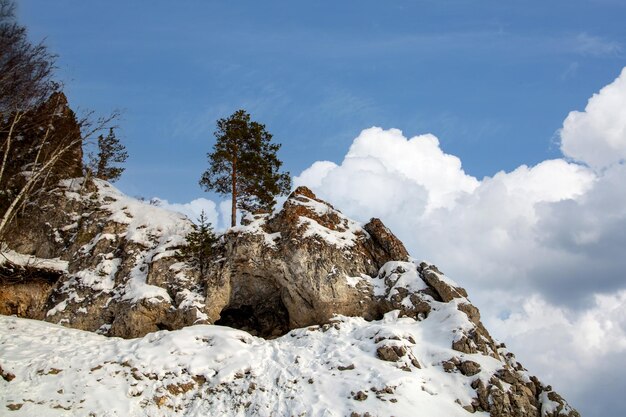 凍った川のほとりの森に覆われた冬の風景の山と岩