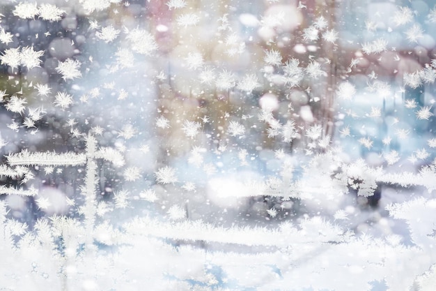 Winter landscape through a frozen window Blurred snow background Trees and plants covered with snow