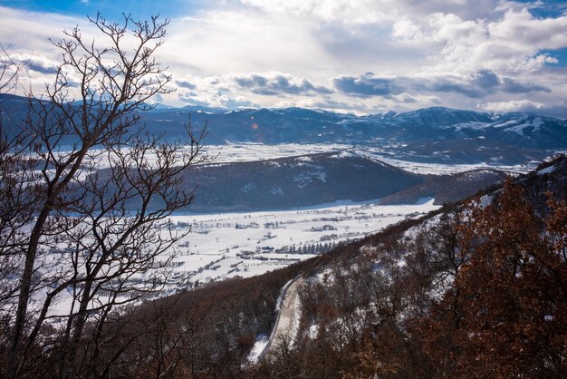 明るい晴れた日に雪で覆われた冬の風景の谷と丘