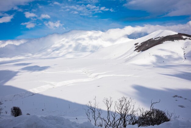 明るい晴れた日に雪で覆われた冬の風景の谷と丘