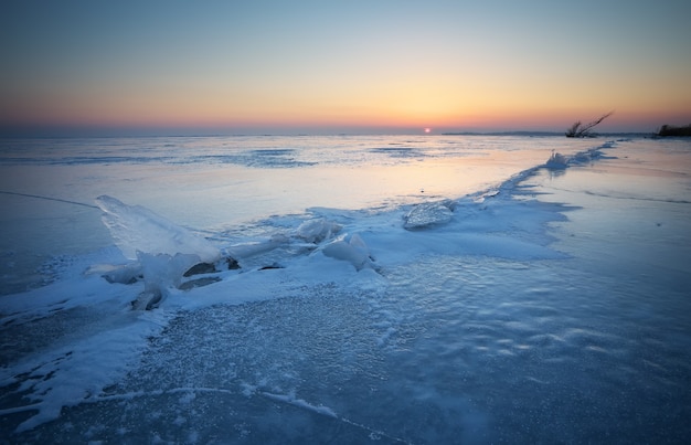 Зимний пейзаж с трещинами на замерзшем озере у берега
