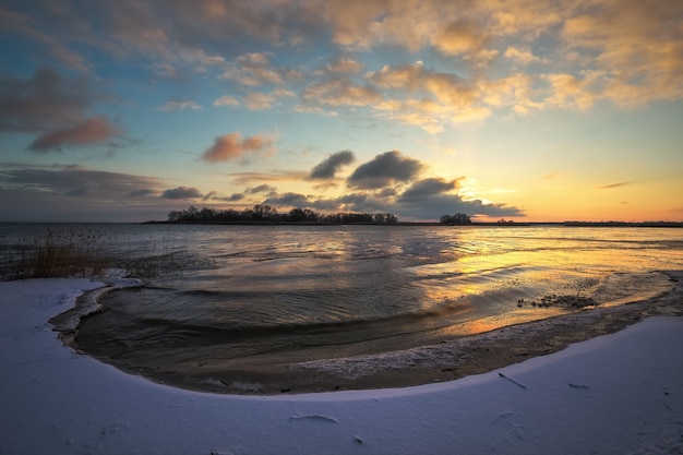 Foto paesaggio invernale con lago ghiacciato e cielo al tramonto. cielo arancione colorato