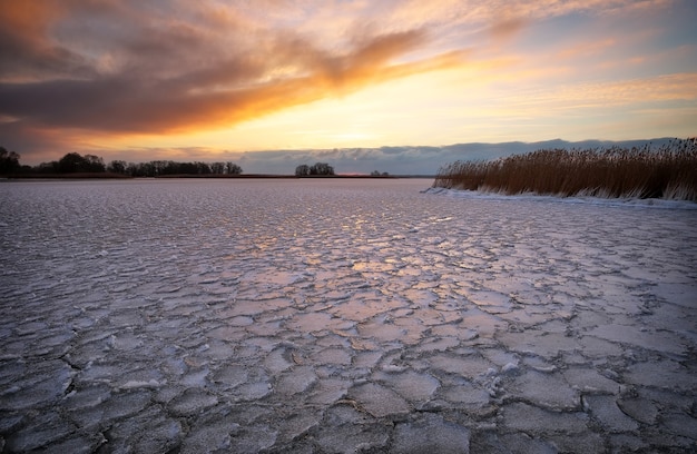 Photo winter landscape with frozen lake and sunset sky. composition of nature.