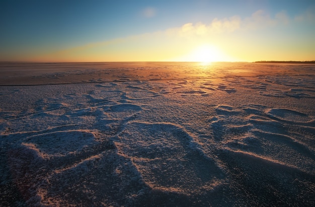 Winter landscape with lake and sunset fiery sky. Composition of nature.