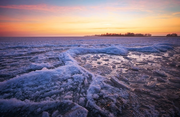 Winter landscape with lake and sunset fiery sky. Composition of nature.