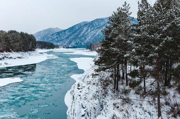 Зимний пейзаж со скалами, камнями и льдом в реке в горах