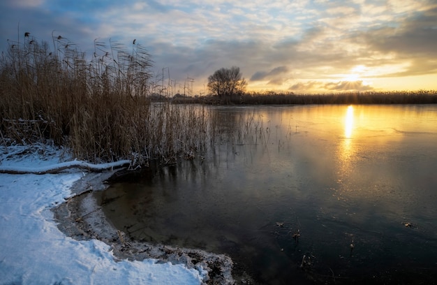 Foto paesaggio invernale con cielo al tramonto e fiume ghiacciato. alba