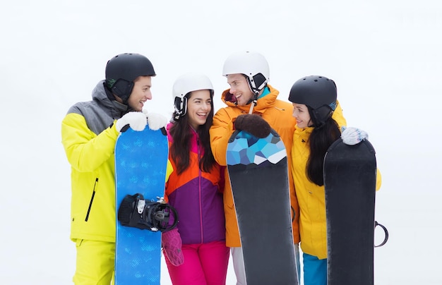 Фото Зима, отдых, экстремальный спорт, дружба и концепция людей - счастливые друзья в шлемах со сноубордом разговаривают