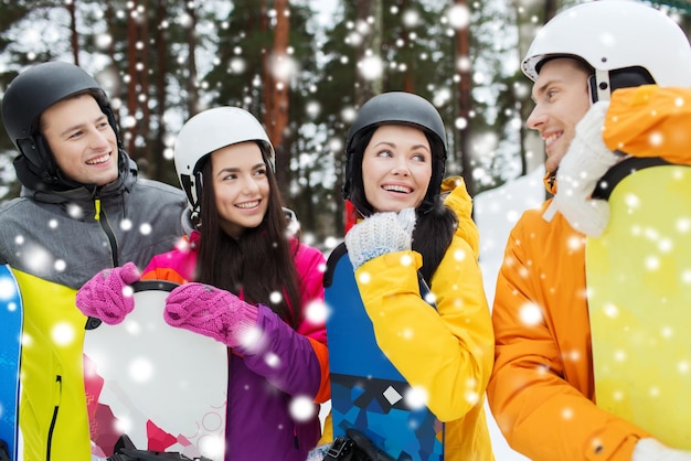 Photo winter, leisure, extreme sport, friendship and people concept - happy friends in helmets with snowboards talking