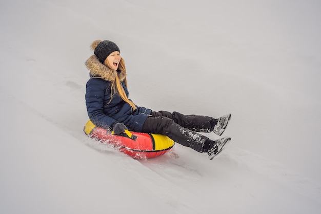 冬のレジャー スポーツの友情と人々 の概念の女性が雪のチューブを滑り落ちる