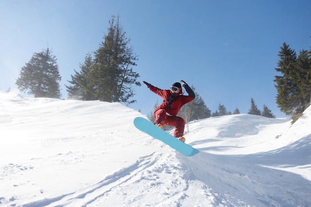 Winter, leisure, sport and people concept - active snowboarder\
jumping in mountains on a sunny day. snowboarding closeup.\
sheregesh ski resort