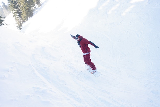 Winter, leisure, sport and people concept - active snowboarder\
jumping in mountains on a sunny day. snowboarding closeup.\
sheregesh ski resort