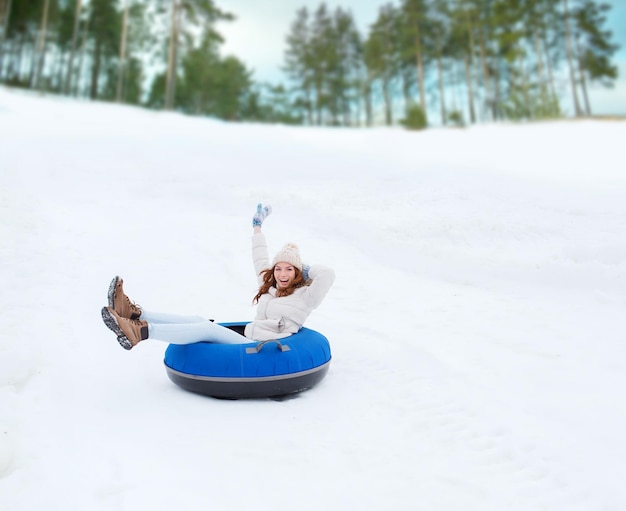 冬、レジャー、スポーツ、そして人々のコンセプト-雪の管の上を滑り落ちる幸せな10代の少女または女性