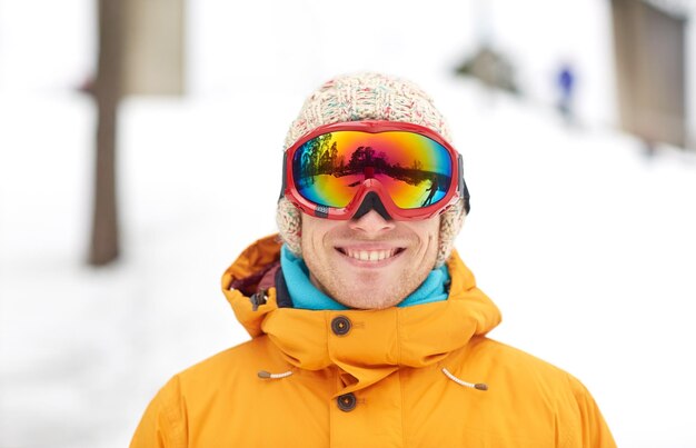 winter, leisure, sport and people concept - happy young man in ski goggles outdoors