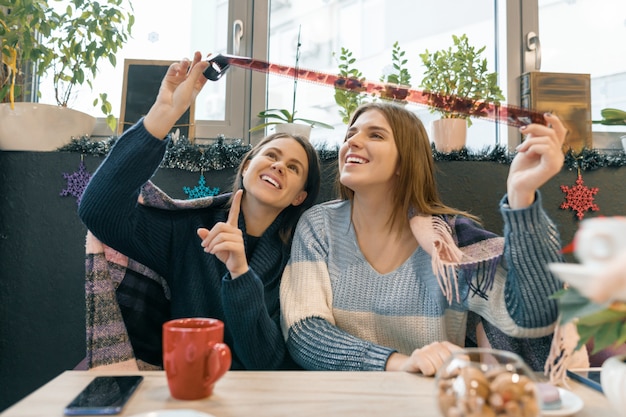 Donne di stile di vita di inverno in caffè divertendosi guardando vecchi rotoli di pellicola