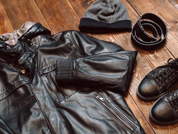 Winter male warm clothes set. Leather jacket boots hat belt on wooden.