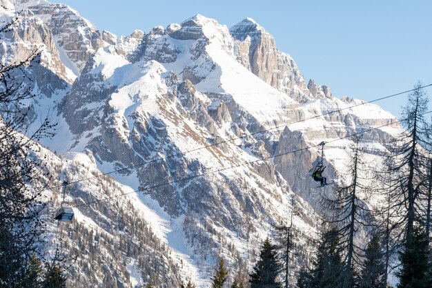 Winter. Mensen beklimmen de stoeltjeslift naar de skipiste te midden van met sneeuw bedekte bergen. Het concept van skiën, landschap.