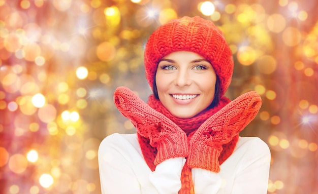 winter, mensen, kerstmis en feestdagen concept - gelukkig lachende vrouw in muts, uitlaatdemper en wanten over lichten achtergrond