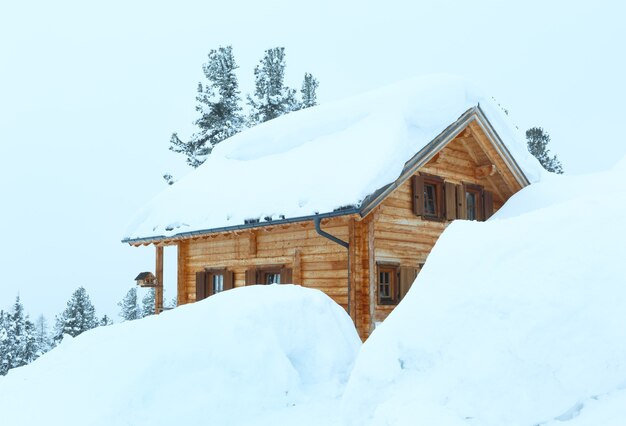 Winter misty mountain landscape and wood house on hill top.