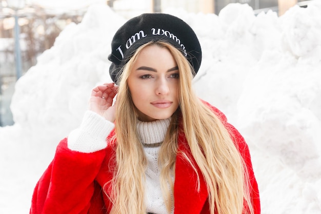 Foto winter, mode, mensen concept - mode portret van een mooie jonge vrouw loopt rond de stad glimlachend rode bontjas close-up sneeuwvlokken koude winter, frisse lucht inademen bij vorst winterdag. zonsondergang