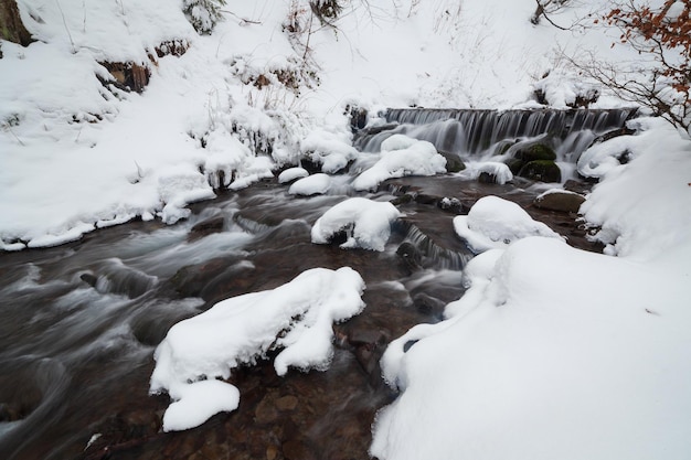 冬の山の滝の雪のシーン雪に覆われた山の滝の風景Shipotの滝の冬の山の滝カルパティア山脈ウクライナ