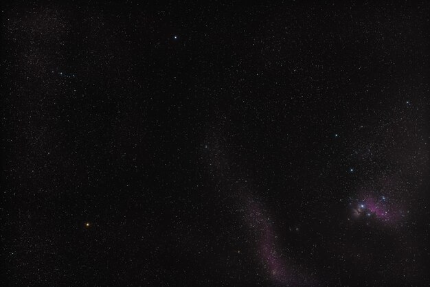 Photo winter night sky at orion constellation, messier 42 nebula in right down corner, bright yellow betelgeuse star left side and blue bellatrix above