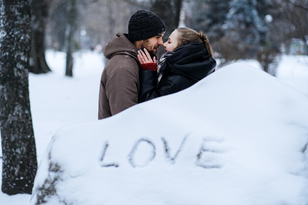 Winter outdoors portrait of Young couple in love and word Love on snow Valentines day outdoors celebration date ideas Winter love story Cold season dating for couples