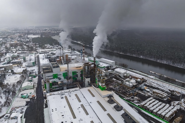Winter panoramic aerial view of dark smoke of pipes of woodworking enterprise with snow Air and water pollution concept