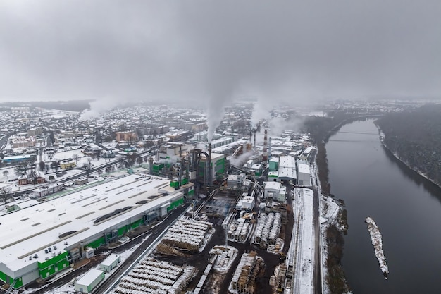 Winter panoramic aerial view of the smoke of pipes of a chemical plant or woodworking enterprise Air and water pollution concept