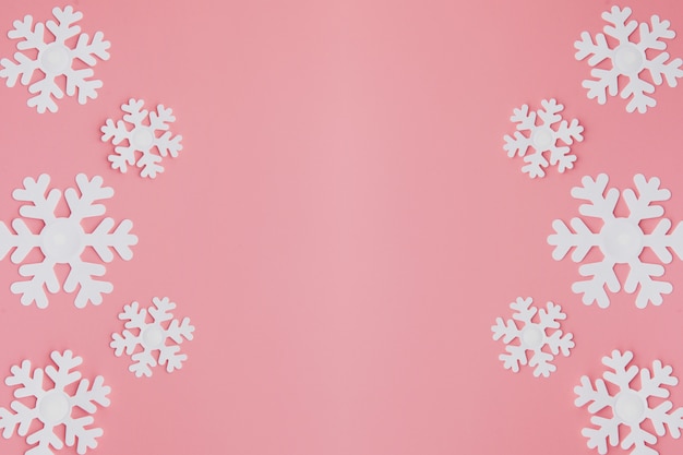 Photo winter pattern made of snowflakes and on pink background.