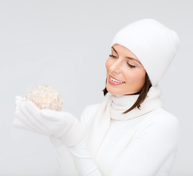 winter, people, happiness concept - woman in hat, muffler and gloves with christmas ball