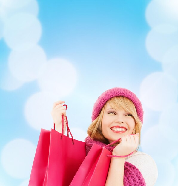 концепция зима, люди и счастье - женщина в розовой шляпе и шарфе с множеством сумок для покупок