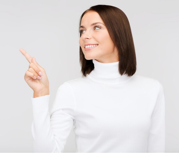 winter, people, happiness concept - woman in white sweater pointing to something