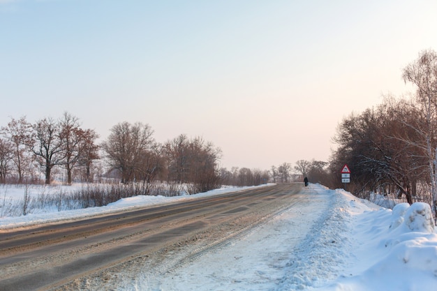 Strada scarsamente pulita invernale. strada in campagna cosparsa di neve. paesaggio invernale con cumuli di neve