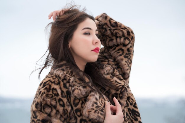 Winter portrait of brunette young woman with long hair\
straightens hair with his hand looking away