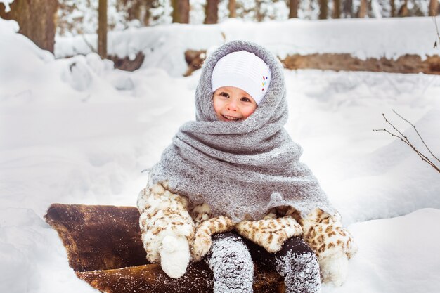맑은 눈 덮인 숲에서 산책에 귀여운 웃는 아이 소녀의 겨울 초상화