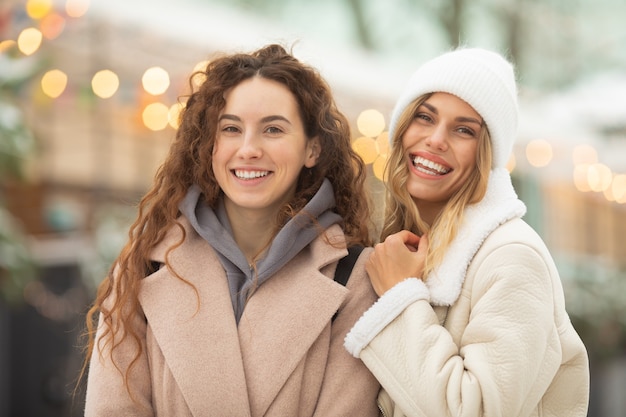 女性の友人を笑顔のファッションの冬の肖像画。屋外で楽しんで幸せな女性。