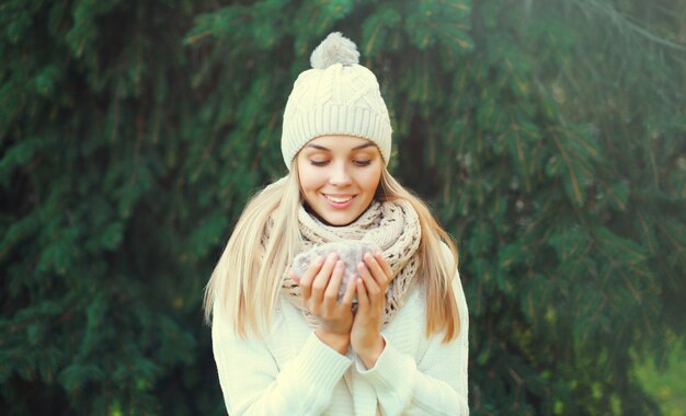 Winter portrait happy woman holds mug of hot coffee in forest on christmas tree background