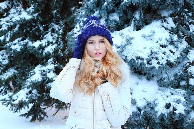 Winter portrait of young beautiful blond woman in her warm clothing in the forest