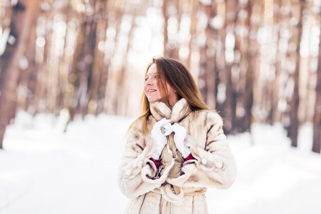 Winter portrait of young beautiful woman wearing fur coat. Snow winter beauty fashion concept.