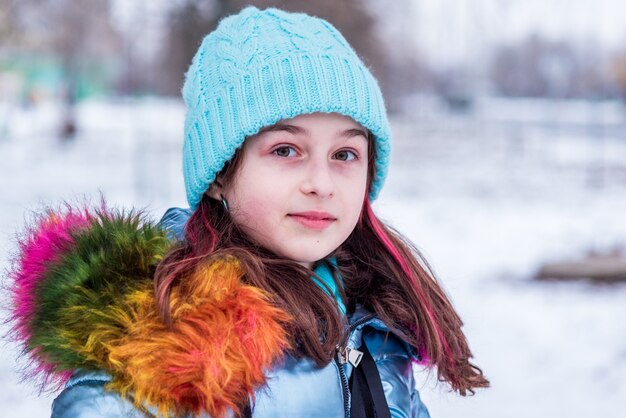 Winter portret van een jong meisje in haar warme kleding. tiener in een blauwe hoed bij sneeuwweer.