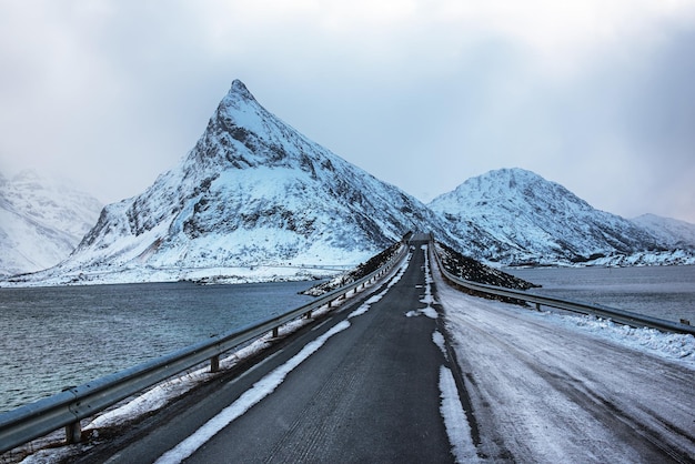 로포텐 제도 노르웨이 여행 배경에 눈 덮인 봉우리가 있는 바다 위의 겨울 도로
