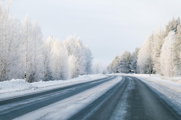 ラップランドの寒いフィンランドの冬の道と雪に覆われた森。