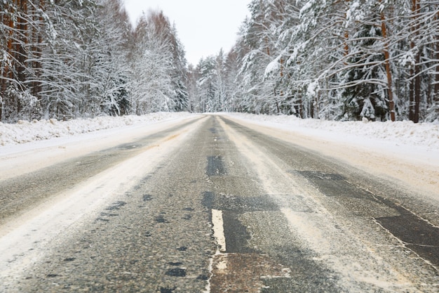 雪に覆われた凍るような森の風景の中の冬の道