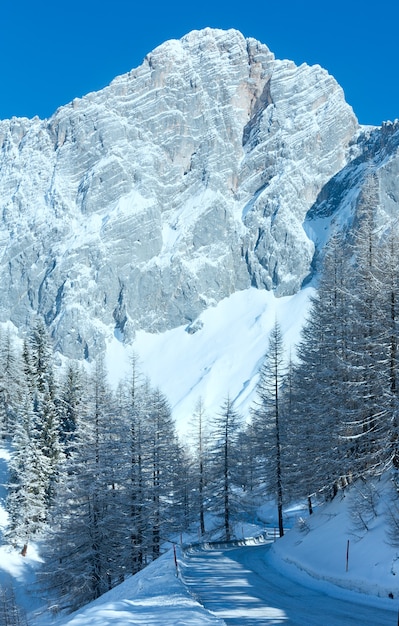 Winter rock with fresh fallen snow on top and and alpine road.